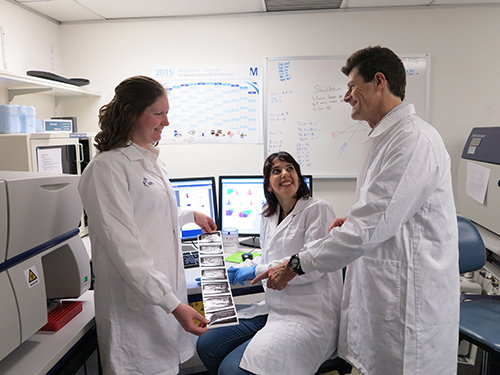 3 people standing in a lab pointing at results
