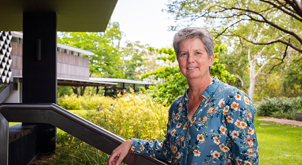 Photograph of Sarah Larkins standing in front of a lush green garden