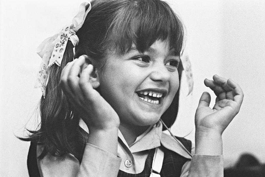 Photograph of Girl Pia Jeffery cupping her ears while smiling .