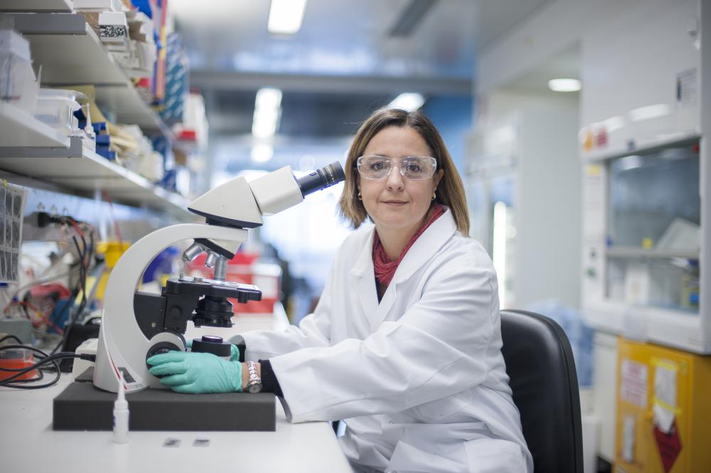 Diana Hansen wearing a white lab coat and blue gloves in a laboratory
