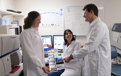 Dr Joanne Reed, Dr Deborah Burnett and Professor Goodnow - all wearing white lab coats and looking at some printouts of a scan.
