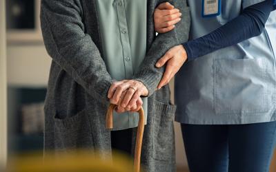 Image sourced from Istock - Nurse interlocked arms with a patient holding onto a walking stick