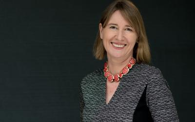 Professor Rebecca Bentley smiling at the camera in front of a black background