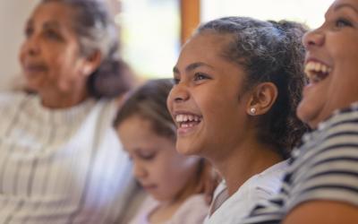 Four Indigenous Australian girls smiling and laughing while looking into the distance