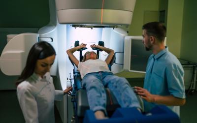 Women laying down about to undergo radiotherapy with 2 doctors standing on either side